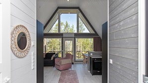 Een modern interieur met een loft-achtige plafond, een gezellige zithoek met een bank en fauteuils, een eettafel en een open haard.