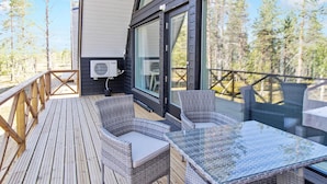 Een houten terras met rieten meubels en een glazen tafel.