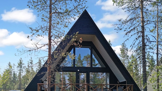 Een moderne, driehoekige houten hut met een groot raam en een houten terras.