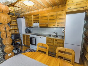 A rustic kitchen with wooden cabinets, a sink, a dishwasher, and a refrigerator.
