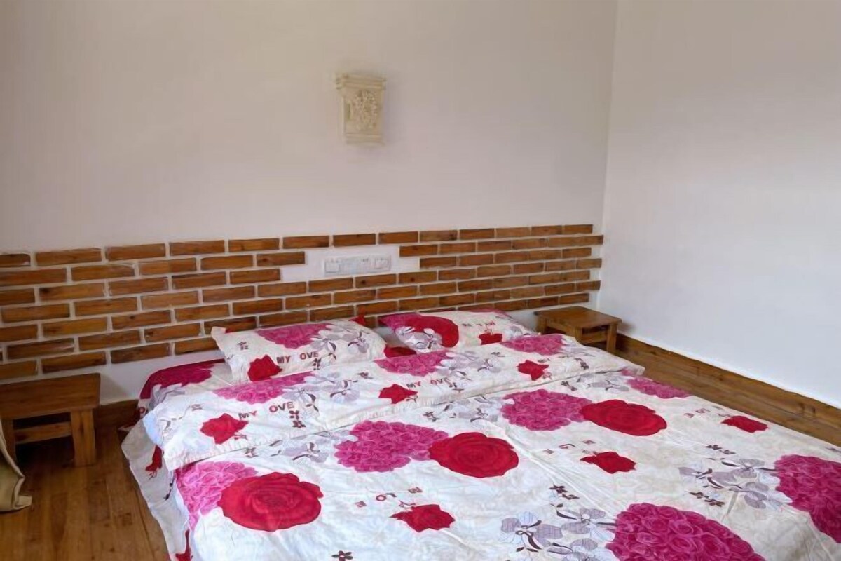 Un dormitorio con cabecera de ladrillo, edredón estampado con flores y una mesita de noche.