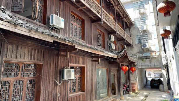 A traditional wooden building with multiple balconies, air conditioning units, and red lanterns. - Tianzishan Inn (Zhangjiajie)