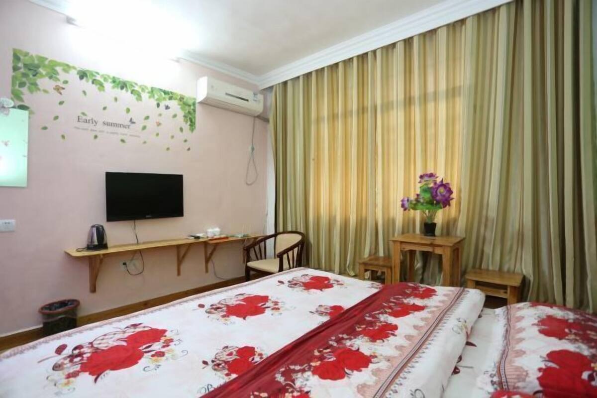 Habitación de hotel con cama, escritorio, silla, televisor y ventana con cortinas.