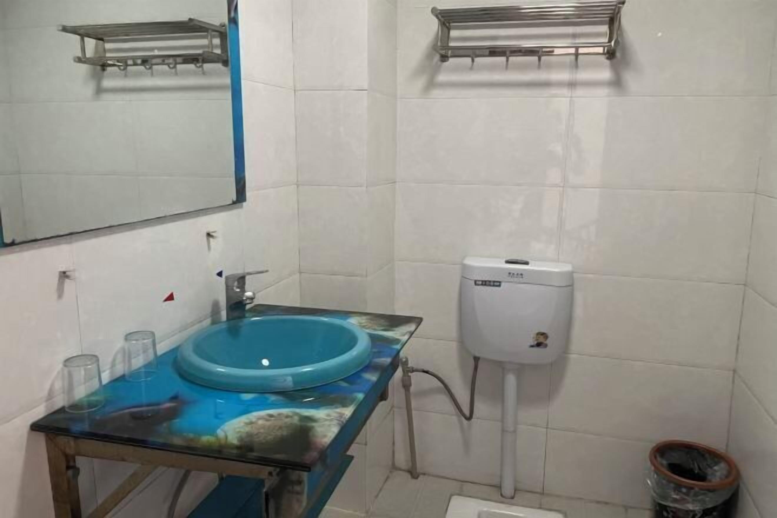A bathroom with a blue sink, a mirror, and a white toilet.