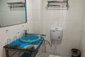 Un baño con un lavabo azul, un espejo y un inodoro blanco.