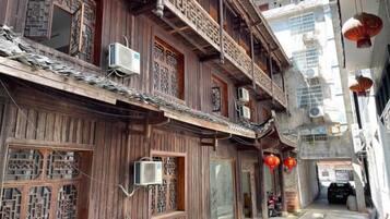 A traditional wooden building with multiple windows and balconies, air conditioning units, and a narrow street.