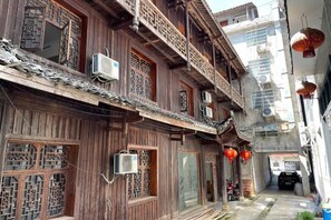A traditional wooden building with multiple windows and balconies, air conditioning units, and a narrow street. - Tianzishan Inn (Zhangjiajie)