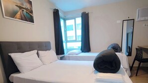 Een hotelkamer met twee bedden, een groot raam met gordijnen, een flatscreen televisie en een schilderij aan de muur.