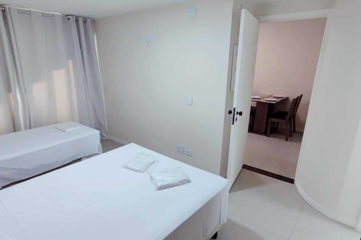 Een hotelkamer met een enkel bed, een klein tafeltje en een stoel.