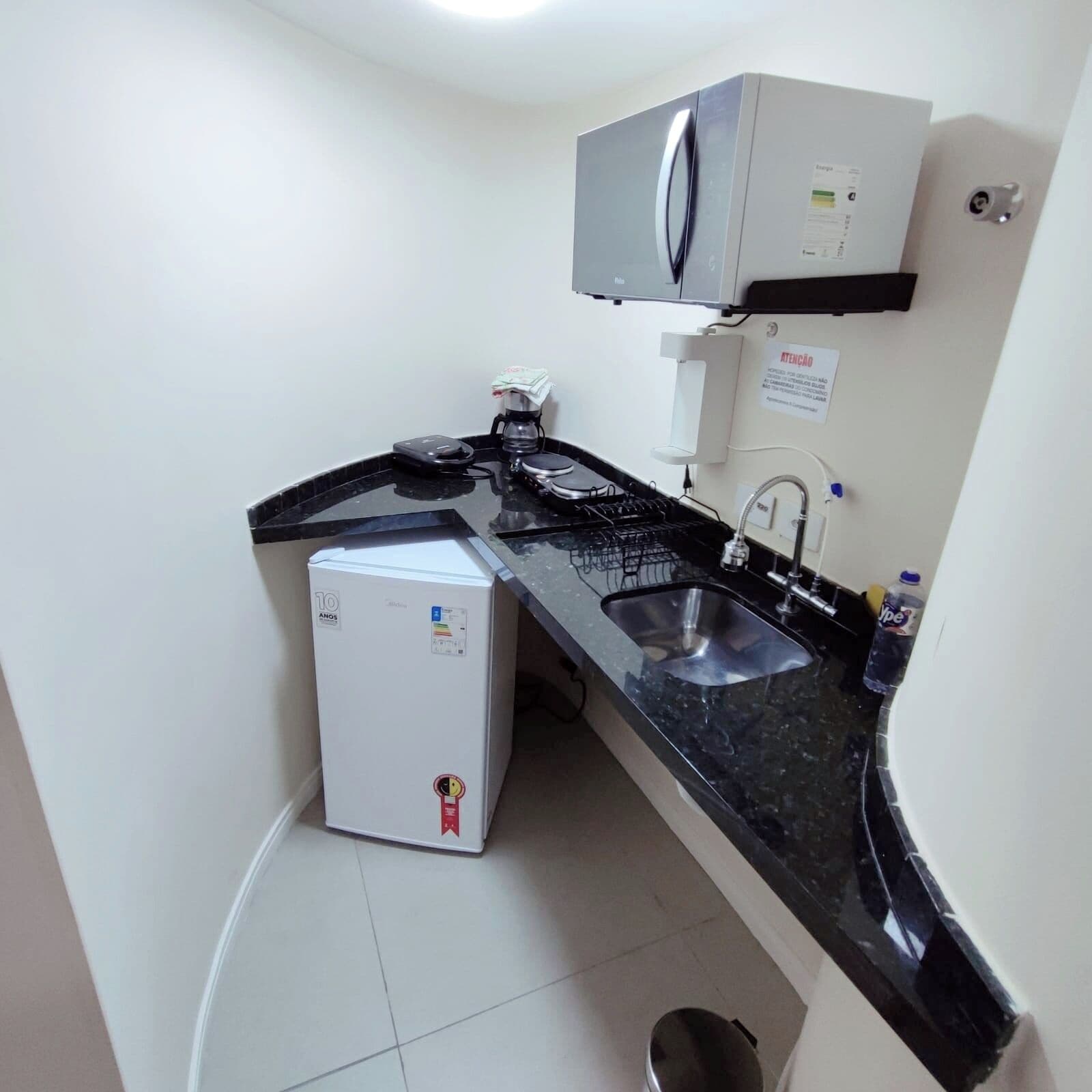 A compact kitchenette with a refrigerator, microwave, sink, and coffee maker.