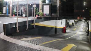 Een modern gebouw met een opvallend cilindervormig ontwerp, met een glazen ingang en een parkeerplaats met pijlen.