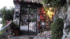 A stone staircase leading to a gated entrance with a sign reading "LA CAS DEL CAPITANO".