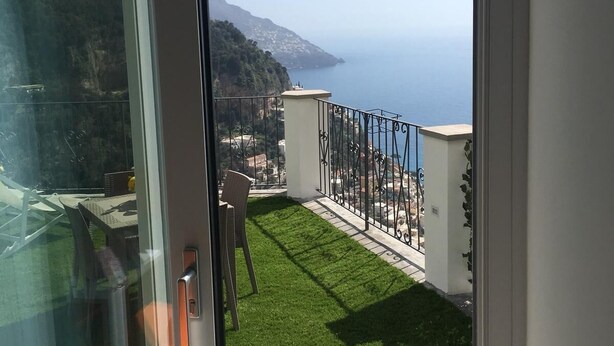 A balcony with a clear view of the sea and a mountainous landscape.