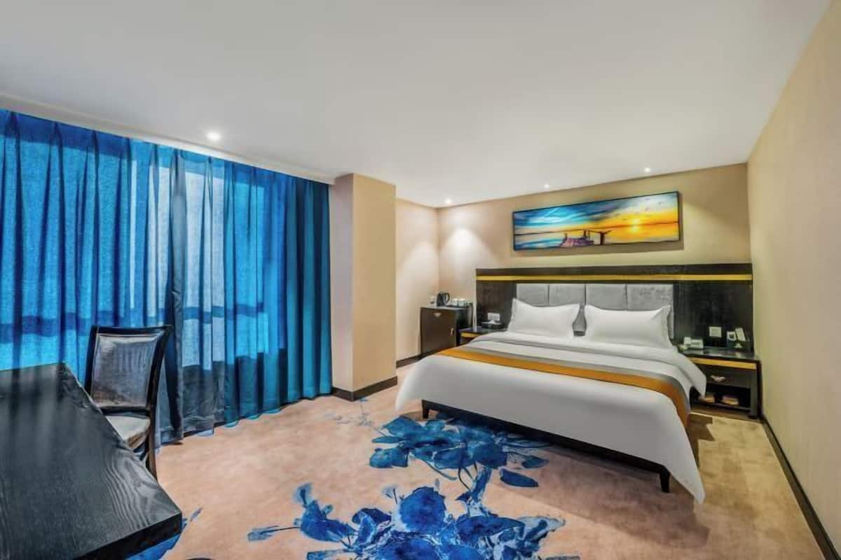 A hotel room with a bed, a desk, and a chair.