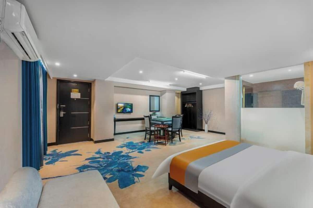 A hotel room with a bed, a desk, a chair, and a shower area.
