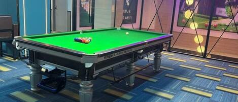 A pool table with balls, a blue carpet, and a room with a door and a wall with a poster.