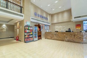 A hotel reception area with a marble counter, vending machines, and a staircase. - Yihe Hotel (Dongguan)