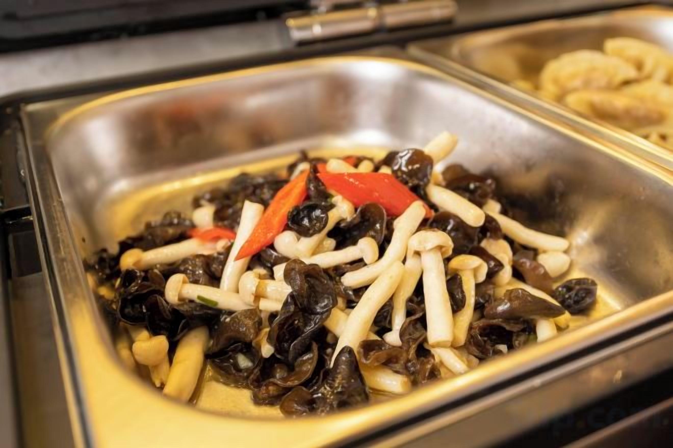 A buffet with various food items including mushrooms and red peppers.