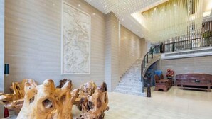 A spacious lobby with a marble floor, a grand staircase, and a large wall mural. - Yihe Hotel (Dongguan)