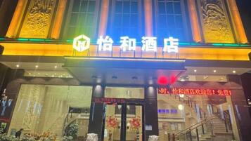 A hotel entrance with a prominent sign, a staircase, and a well-lit facade.