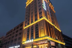 A multi-story hotel with a prominent corner entrance, large windows, and a well-lit facade. - Yihe Hotel (Dongguan)