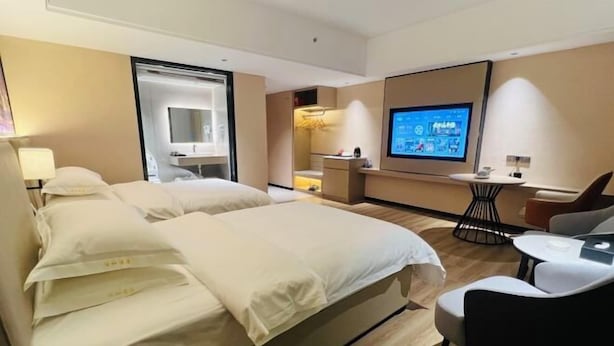 A hotel room with a large bed, a desk with a chair, a television, and a small table. - Yihe Hotel (Dongguan)