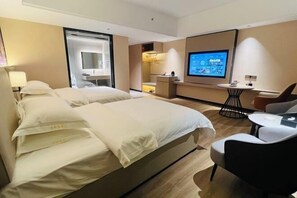 A hotel room with a large bed, a desk with a chair, a television, and a small table. - Yihe Hotel (Dongguan)