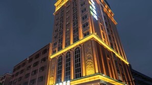 A multi-story hotel with a prominent corner entrance, large windows, and illuminated signage. - Yihe Hotel (Dongguan)