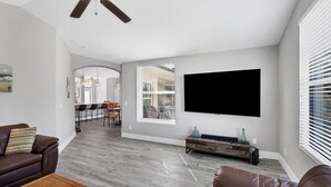 Een moderne woonkamer met een flatscreen televisie aan de muur, een houten salontafel en een bruine leren bank.