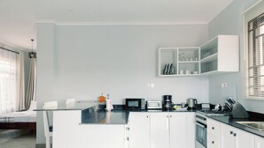 Una cocina moderna con armarios blancos, encimera negra y microondas empotrado.