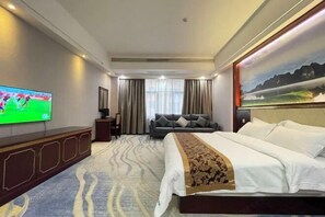 A hotel room with a large bed, a television on the wall, a sofa, and a painting. - Donglan Dongsheng International Grand Hotel (Wei Baqun Memorial Hall Cultural Square) (Donglan)