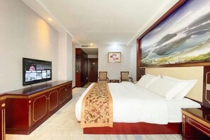 A hotel room with a bed, a television on a cabinet, a painting on the wall, and a desk with a chair. - Donglan Dongsheng International Grand Hotel (Wei Baqun Memorial Hall Cultural Square) (Donglan)