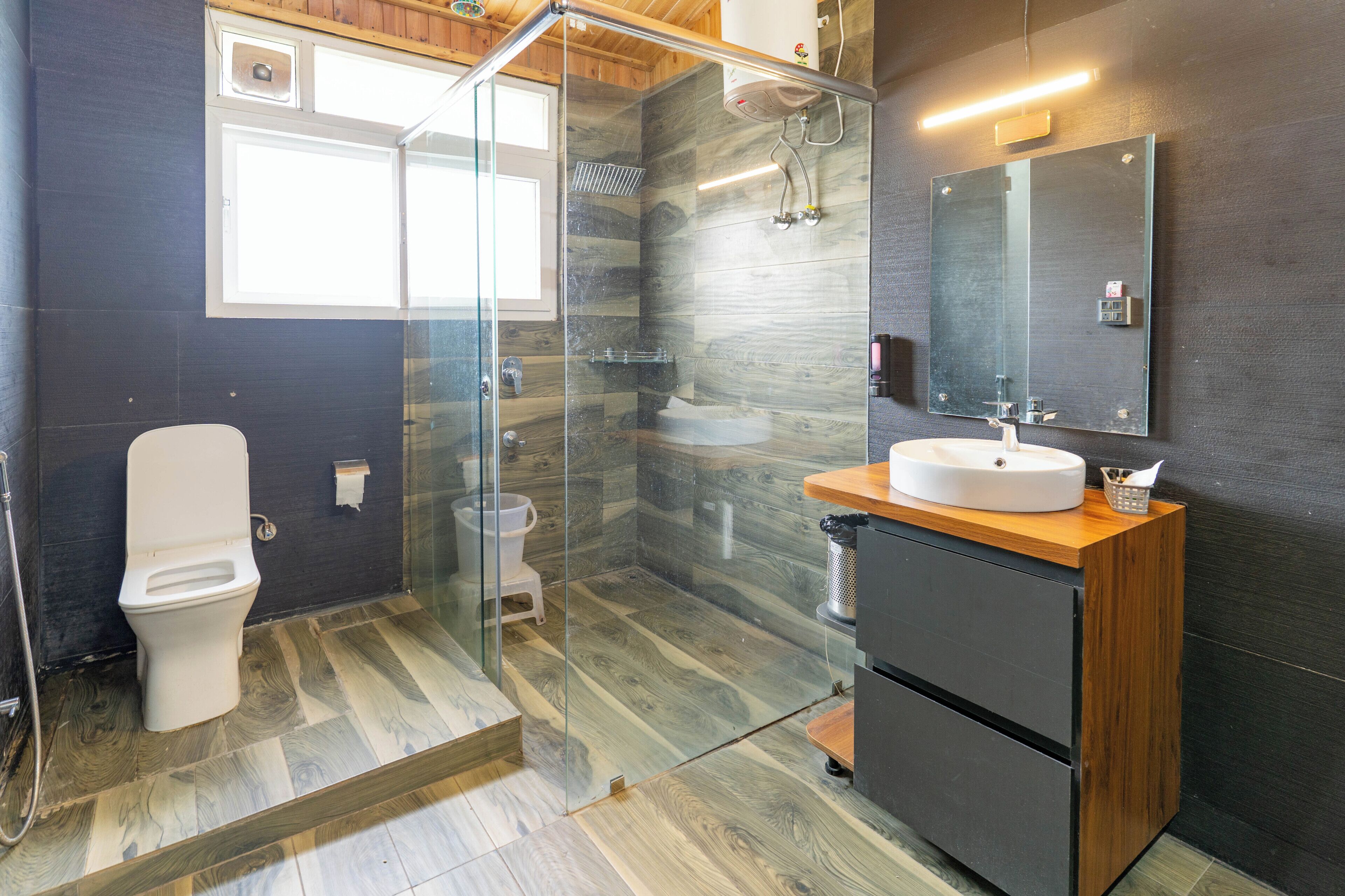 A modern bathroom with a glass shower enclosure, a toilet, and a sink with a mirror.