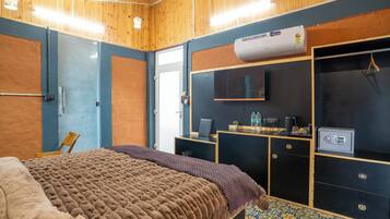 A bedroom with a bed, a desk, a wardrobe, and an air conditioning unit.