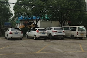 Un parking avec plusieurs voitures et un fourgon blanc.