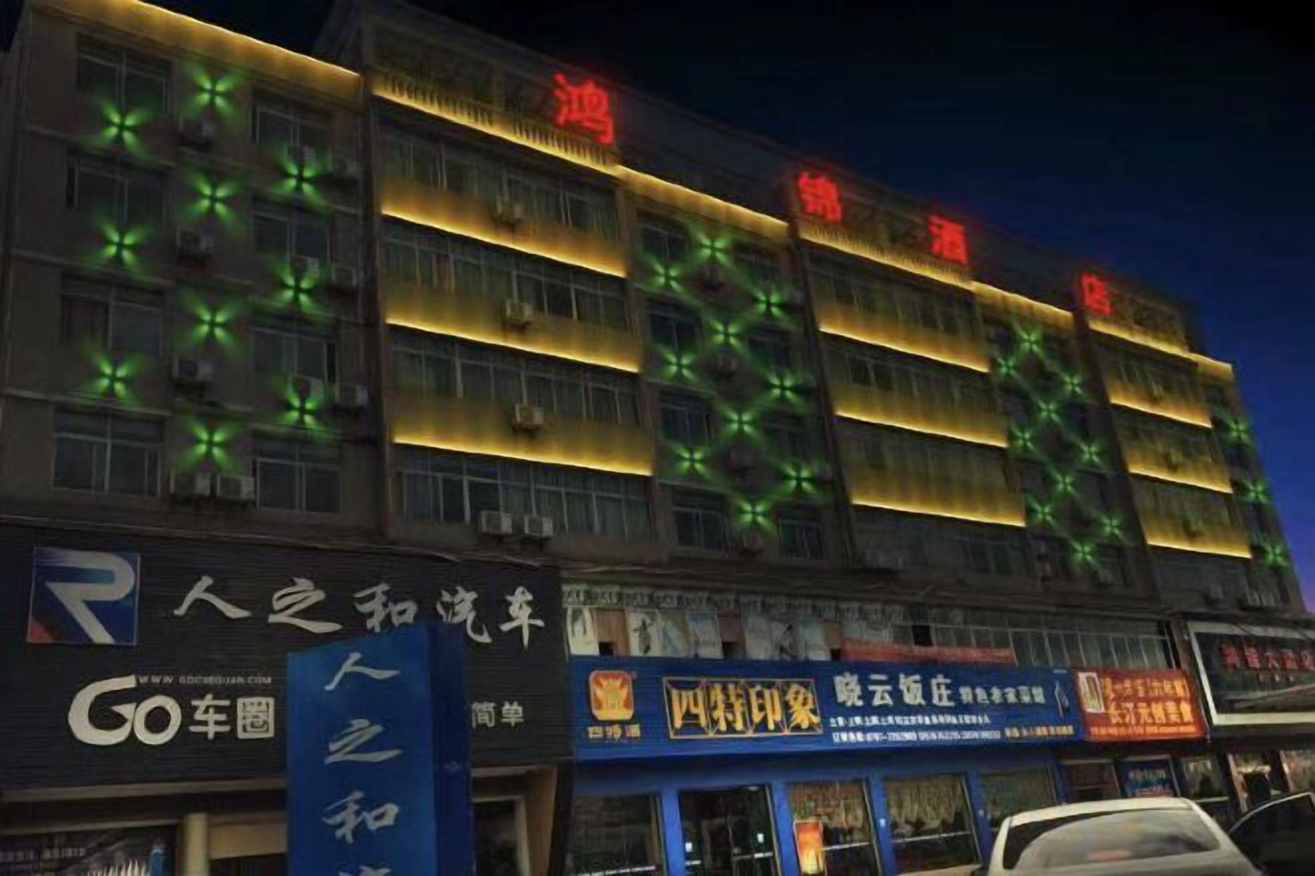 A multi-story building with illuminated signage and air conditioning units.