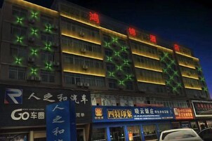 Un edificio de varios pisos con señalización iluminada y unidades de aire acondicionado.
