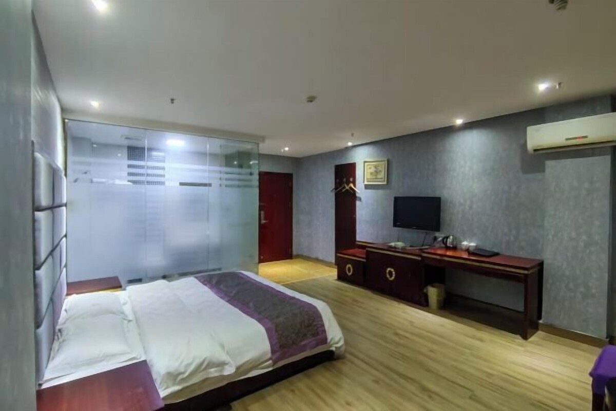 Un dormitorio con cama, escritorio, televisor y armario.