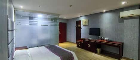 A bedroom with a bed, a desk, a television, and a wardrobe.
