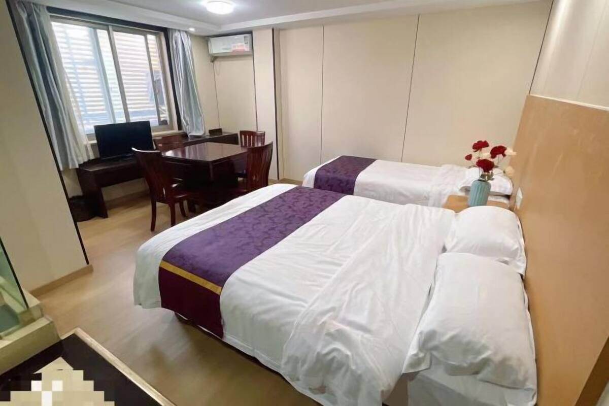 Habitación de hotel con dos camas, un escritorio, una silla y un televisor.