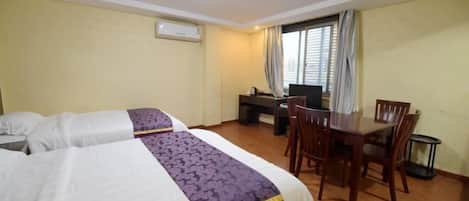 A hotel room with two beds, a desk, and a dining table.