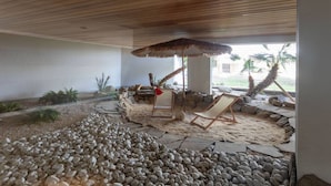 An indoor area with a stone pathway, wooden ceiling, and a seating area with a chair and an umbrella.