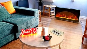 A modern living room with a green sofa, a round coffee table with a decorative item, a fireplace, and a skylight.