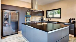 A modern kitchen with a central island, built-in appliances, and a large window providing natural light. - Tulum Dream Villa: Designer Luxury Near The Beach (Tulum)