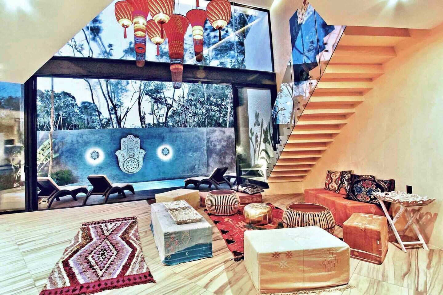 Un interior moderno con un ventanal amplio, una escalera y diversos muebles tradicionales y contemporáneos.