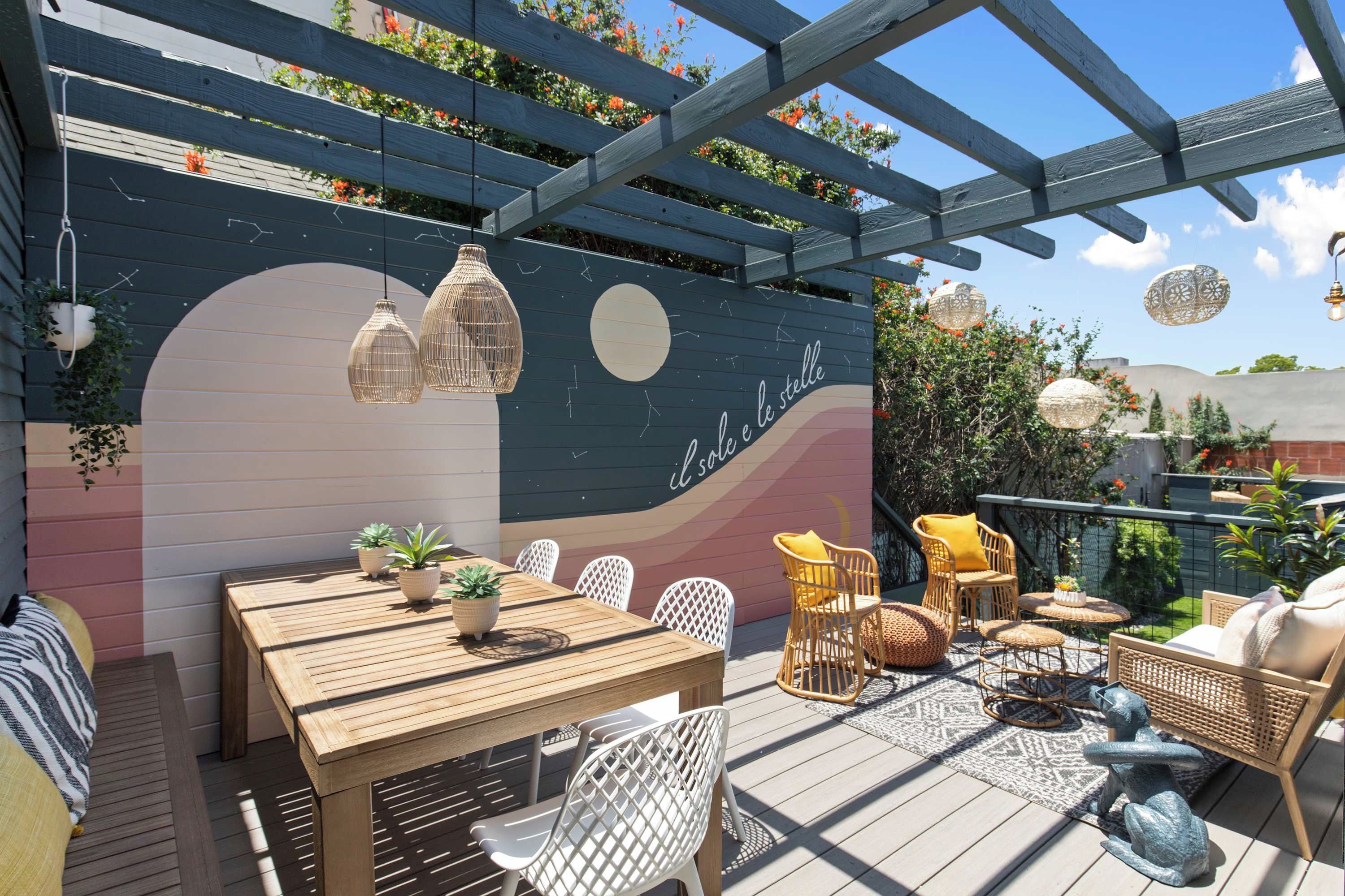 Eine Holzterrasse mit Tisch, Stühlen, einer Pergola und hängenden Lampen.