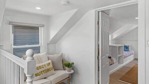 A cozy attic bedroom with a built-in bed, a small seating area with cushions, and a window. - 5BR (Sleeps 12!)  Downtown Little Italy Home w/ Outdoor Space (San Diego)
