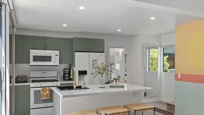A modern kitchen with a central island, built-in appliances, and bar stools. - 5BR (Sleeps 12!)  Downtown Little Italy Home w/ Outdoor Space (San Diego)