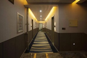 A hotel hallway with a carpeted floor, doors on both sides, and overhead lighting. - Manzhouli Crown Inn (Manzhouli)
