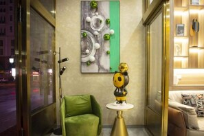 A hotel room with a green armchair, a small white table, and a decorative golden figure. - Manzhouli Crown Inn (Manzhouli)